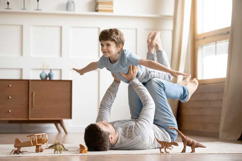 Joyful,Young,Man,Father,Lying,On,Carpet,Floor,,Lifting,Excited